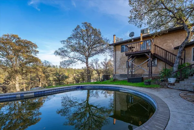 a view of a swimming pool on a sunny day with lawn chairs