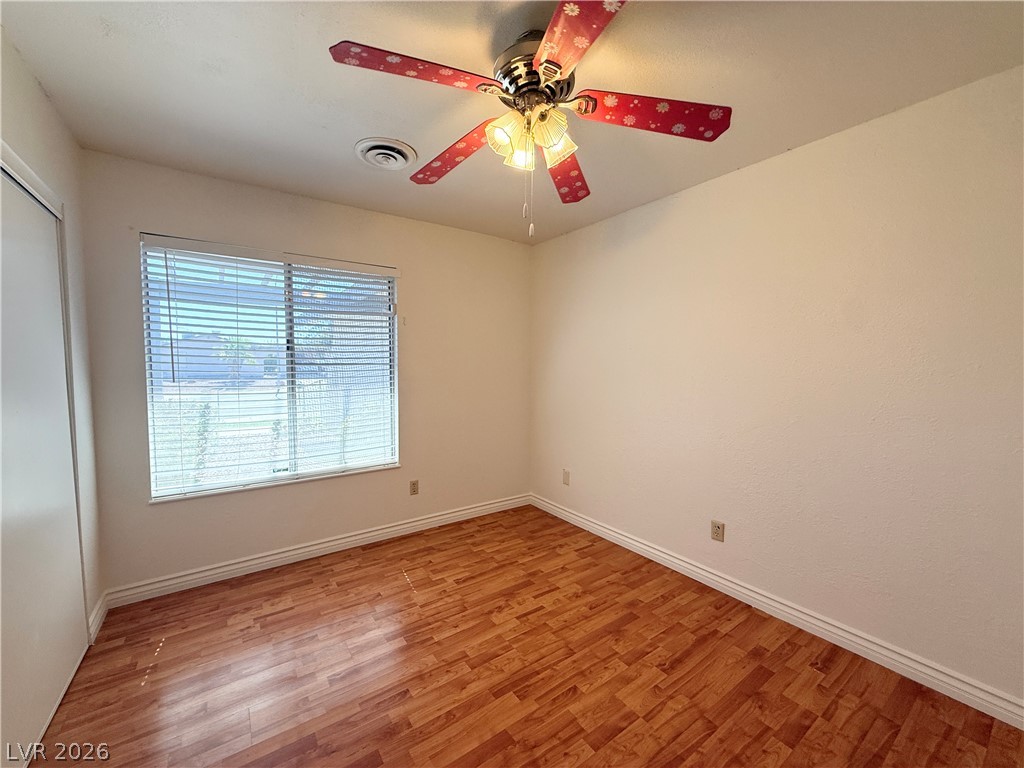 616 Greenway Road Henderson, NV 89002 - Photo 23 of 32 A well-lit bedroom features warm-toned hardwood flooring and a functional window with blinds.