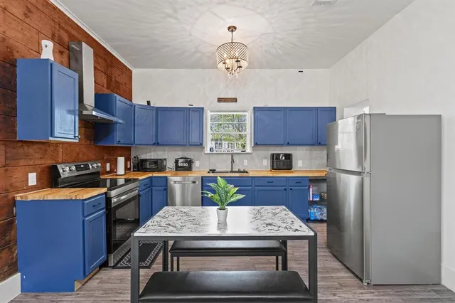 a kitchen with stainless steel appliances granite countertop a refrigerator a sink dishwasher a stove and wooden cabinets