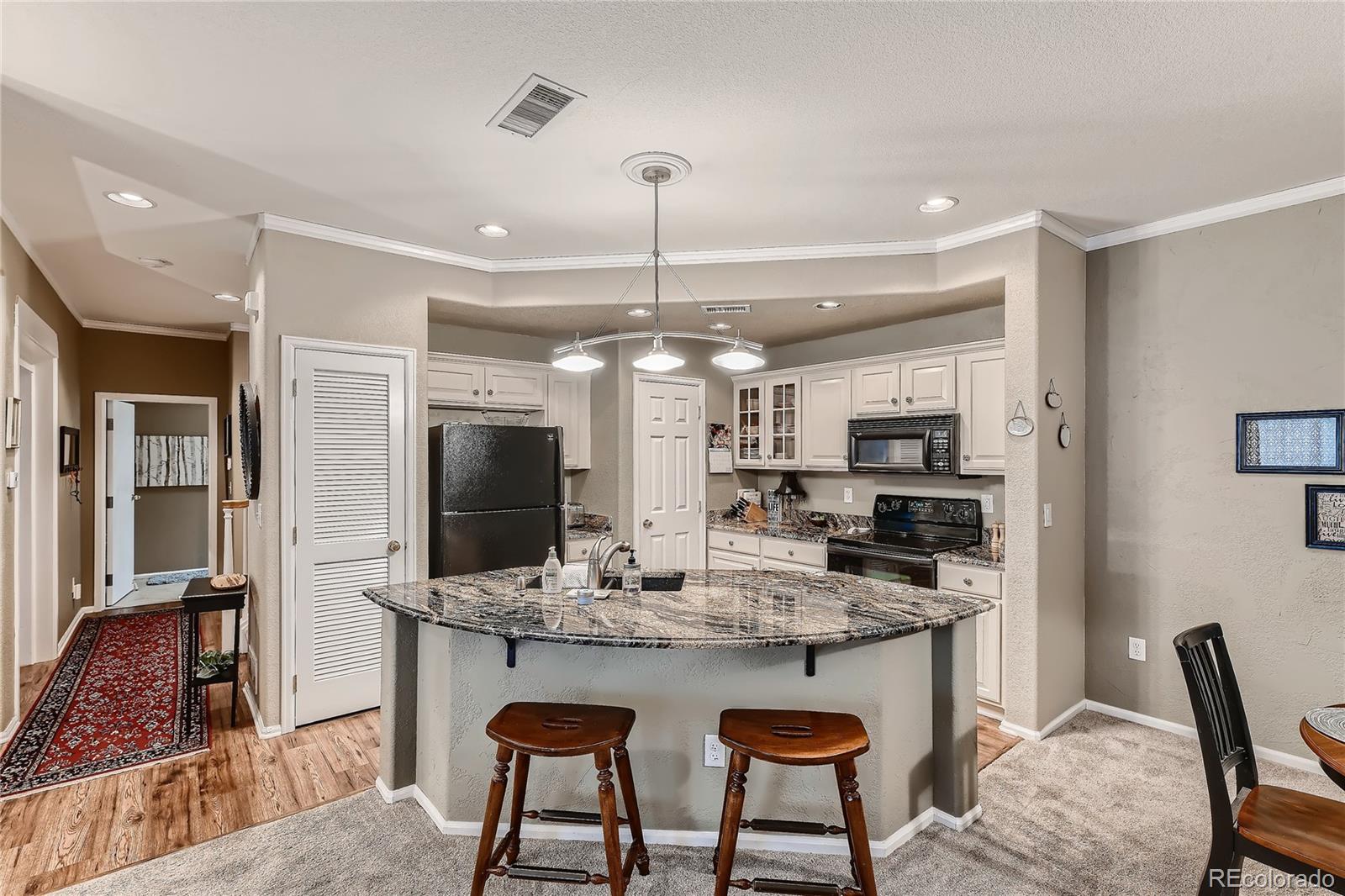 166 Whitehaven Circle Highlands Ranch, CO 80129 - Photo 11 of 28 a kitchen with kitchen island granite countertop a table and chairs