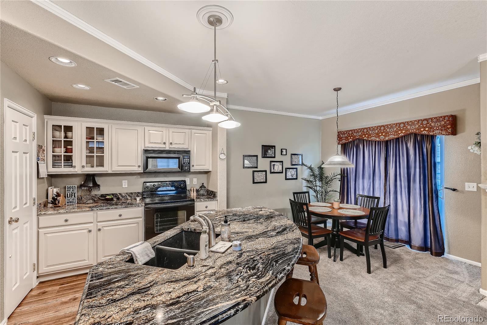 166 Whitehaven Circle Highlands Ranch, CO 80129 - Photo 12 of 28 a kitchen with kitchen island a stove a table and chairs in it