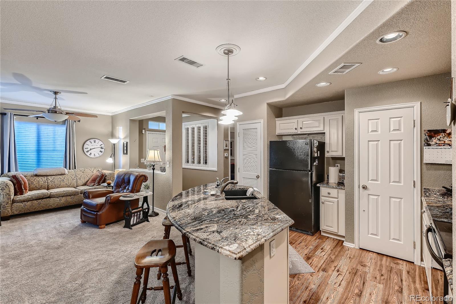 166 Whitehaven Circle Highlands Ranch, CO 80129 - Photo 10 of 28 a living room with furniture a dining table and a refrigerator
