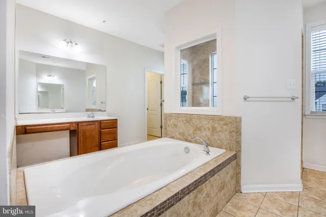 a spacious bathroom with a tub sink and mirror