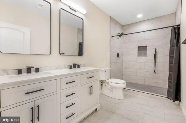 a bathroom with a granite countertop sink toilet a large mirror a shower and vanity