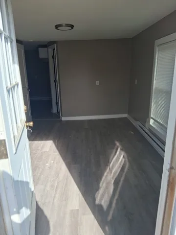 a view of an empty room with wooden floor and a window