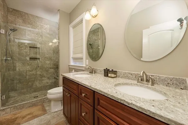 a bathroom with a granite countertop toilet a sink and a mirror