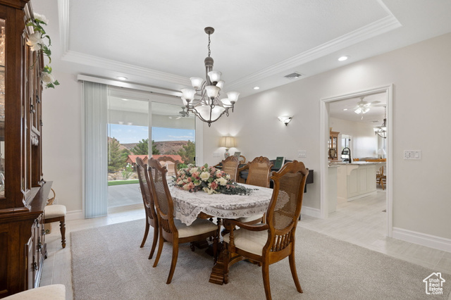 230 Boulder Way Leeds, UT 84746 - Photo 7 of 72 Main formal dining room featuring crown molding, a ceiling fan, sconces, recessed lighting, a tray ceiling, 3-tone paint and light colored carpet with sliding glass doors to the rear covered patio.
