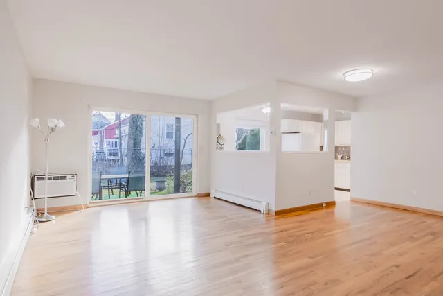 a view of an empty room with wooden floor and windows