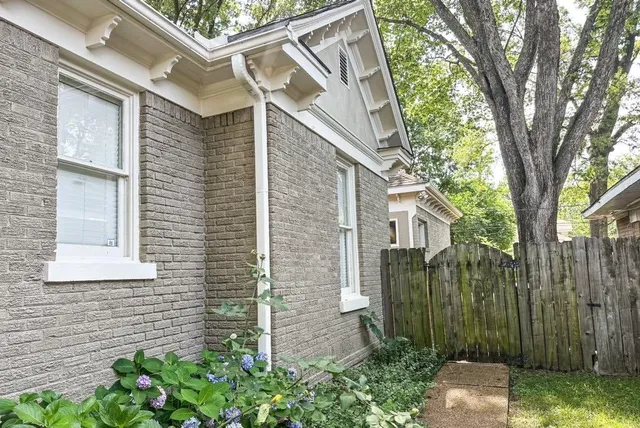 a view of a brick house next to a yard with plants