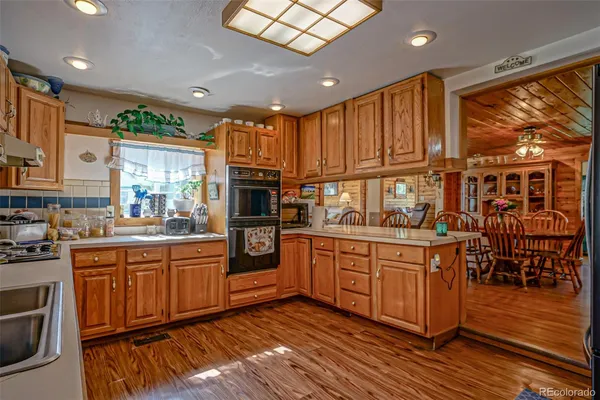 a kitchen with stainless steel appliances granite countertop wooden cabinets a sink a stove a dining table and chairs