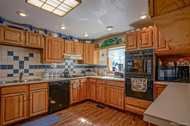 a kitchen with stainless steel appliances granite countertop a stove a sink dishwasher and cabinets with wooden floor