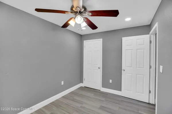 an empty room with wooden floor chandelier fan and closet