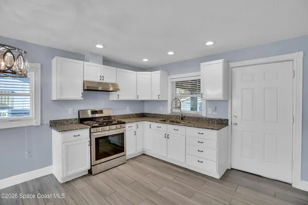 a kitchen with granite countertop white cabinets and white appliances