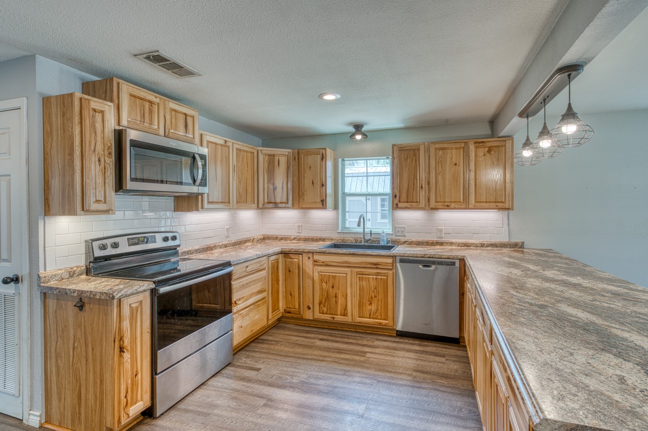 609 Dickson Street Lexington, TX 78947 - Photo 2 of 36 a kitchen with granite countertop wooden cabinets stainless steel appliances and a sink