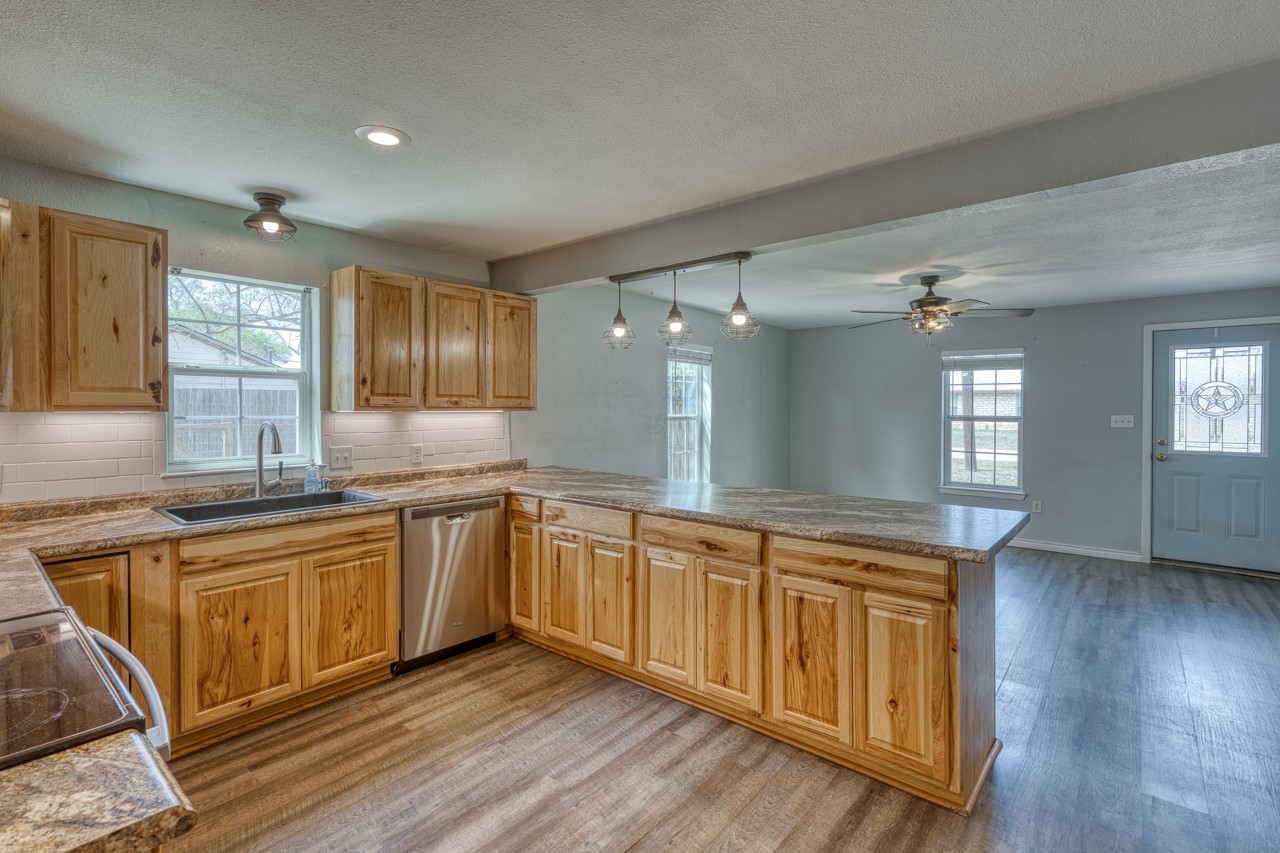 609 Dickson Street Lexington, TX 78947 - Photo 3 of 36 a large kitchen with stainless steel appliances granite countertop a sink dishwasher a stove and white cabinets with wooden floor