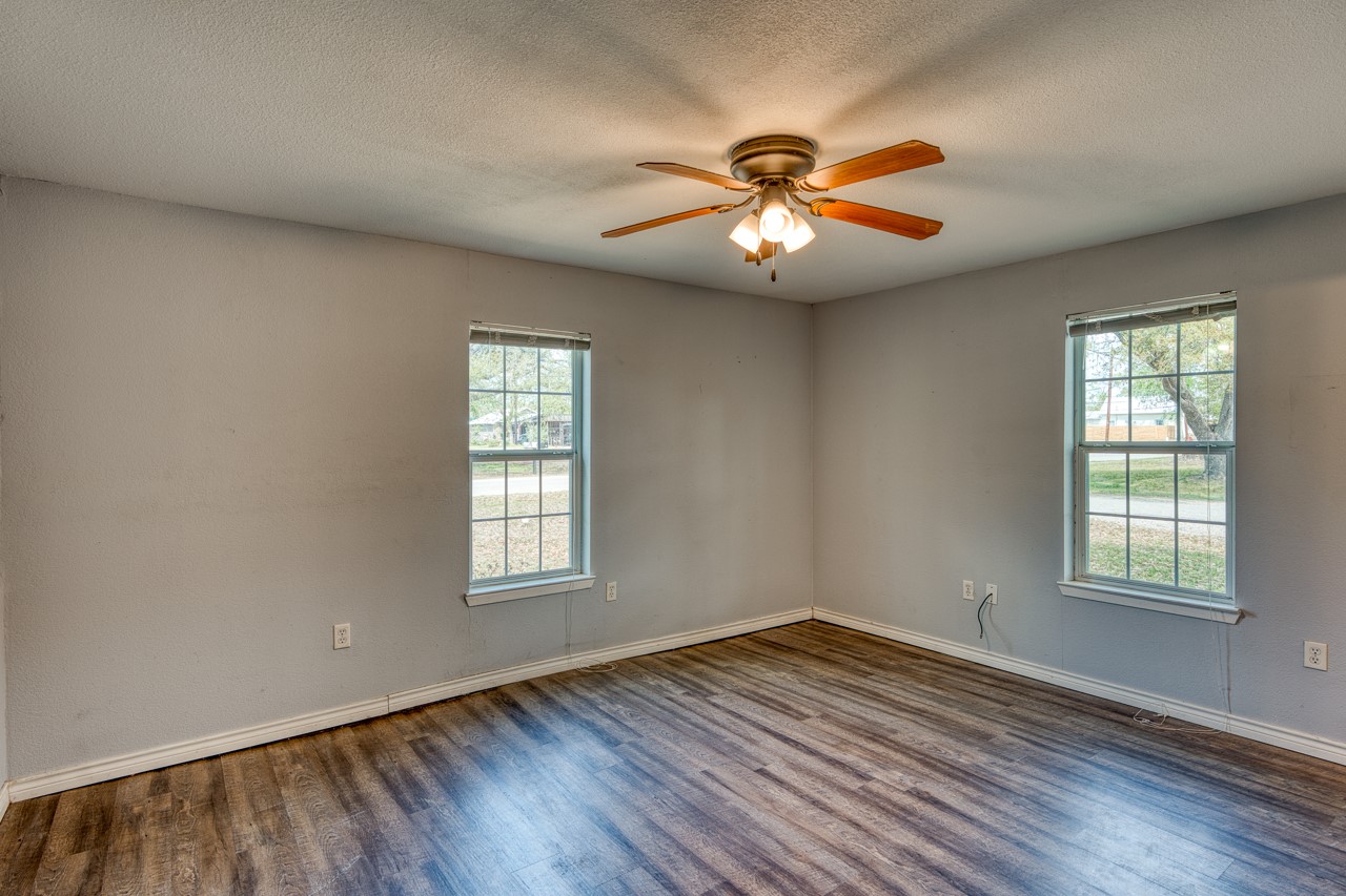 609 Dickson Street Lexington, TX 78947 - Photo 8 of 36 an empty room with wooden floor chandelier fan and windows