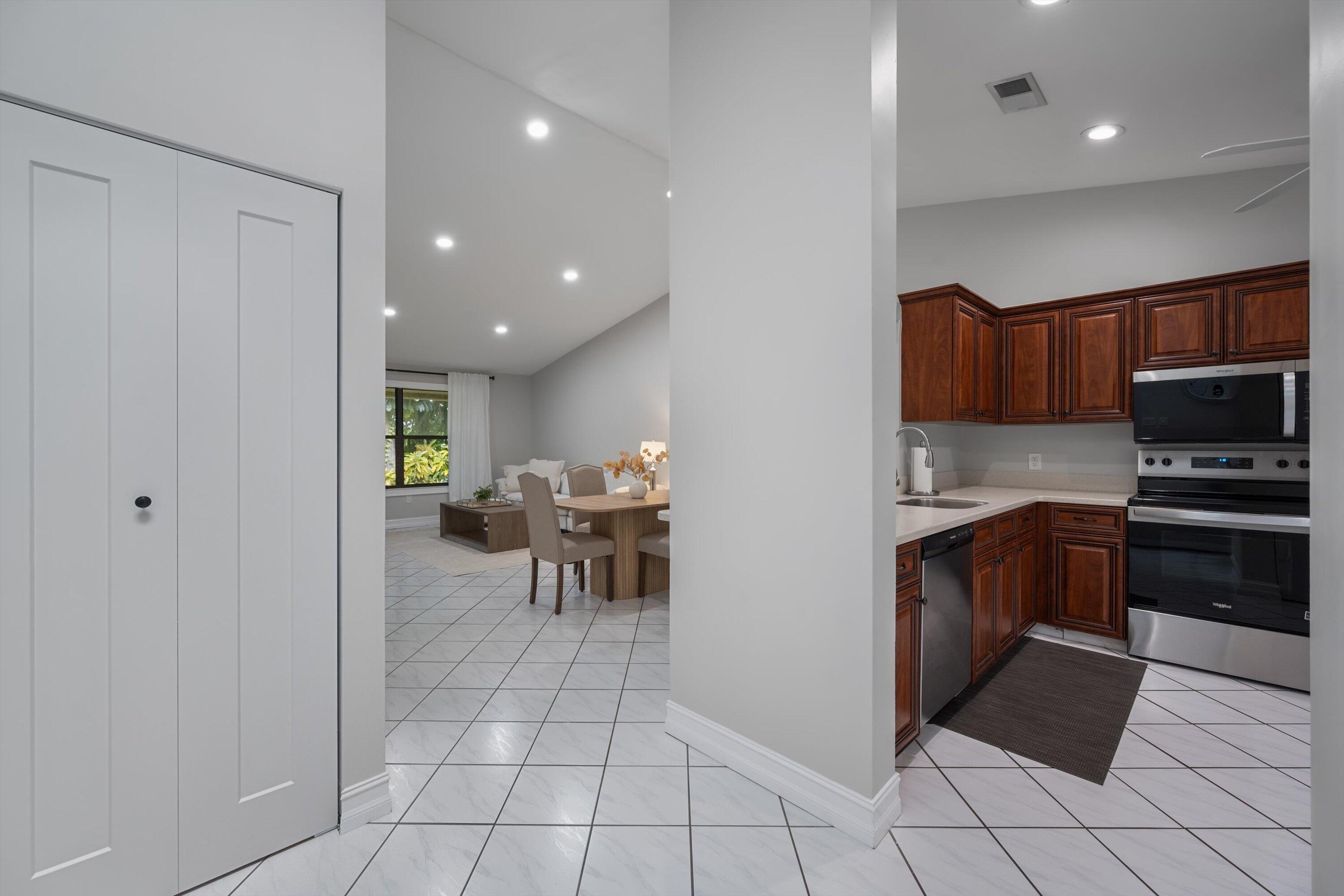 12970 Dartford Trail, Unit 4 Wellington, FL 33414 - Photo 11 of 23 a kitchen with stainless steel appliances a stove a sink a microwave a dining table and chairs