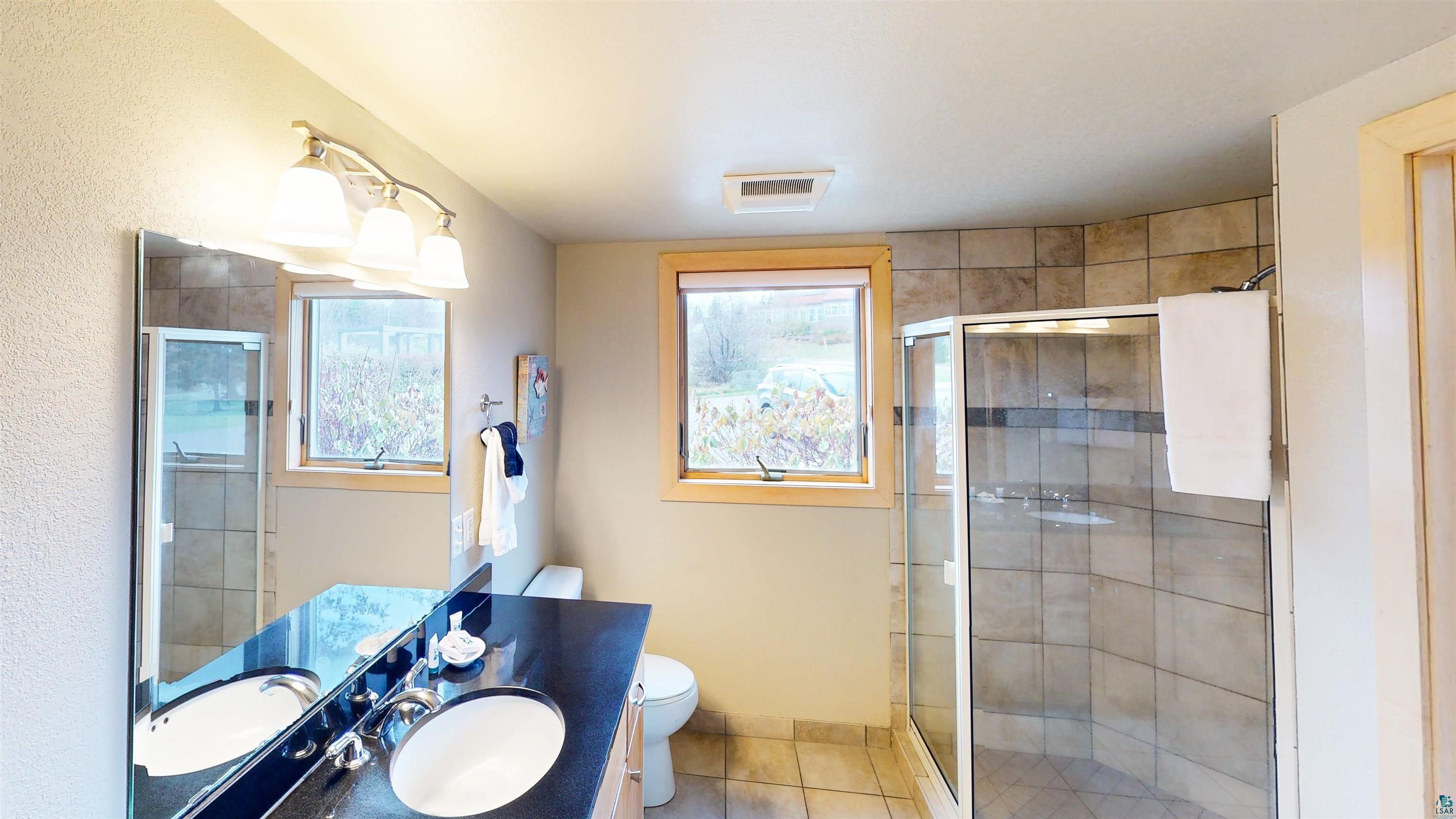 40 Surfside Drive, Unit 5D Tofte, MN 55615 - Photo 15 of 37 Dual vanity with undermount sinks, a dark countertop, and a large mirror