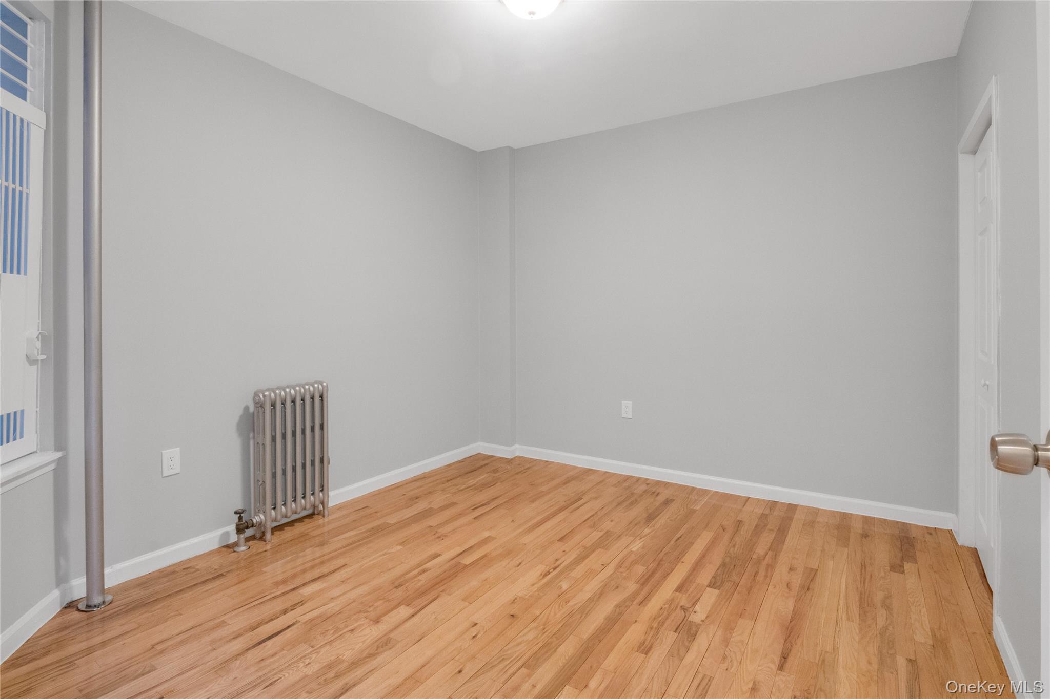2410 Davidson Avenue, Unit B5 Bronx, NY 10468 - Photo 8 of 10 Unfurnished room featuring radiator and light hardwood / wood-style floors
