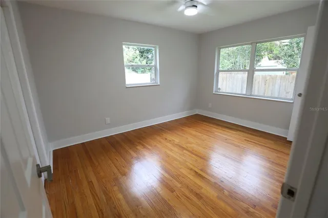 an empty room with wooden floor and windows