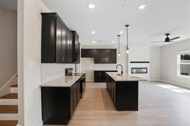 a kitchen with stainless steel appliances kitchen island granite countertop a sink and a refrigerator