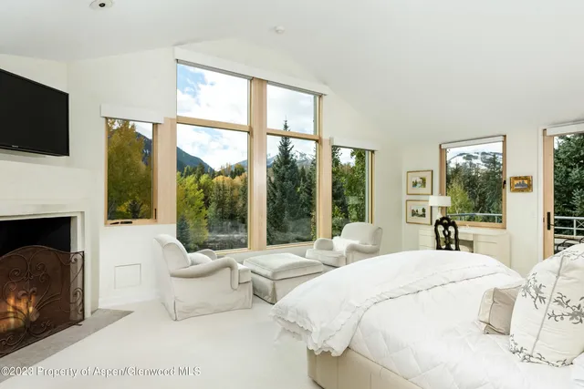 a large bedroom with a large window and a fireplace