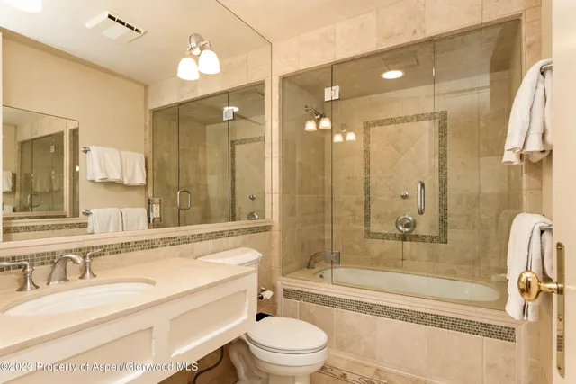 a bathroom with a granite countertop tub toilet sink and mirror