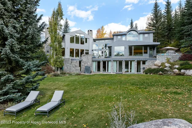 a view of a house with a big yard plants and large trees