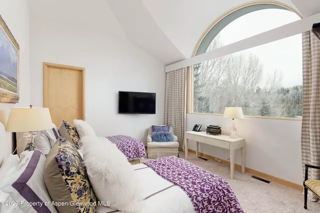 a bedroom with a bed and large windows