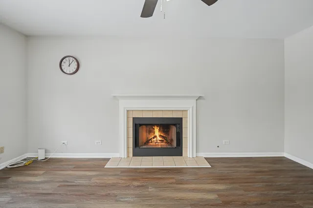 a view of an empty room with wooden floor and a fireplace