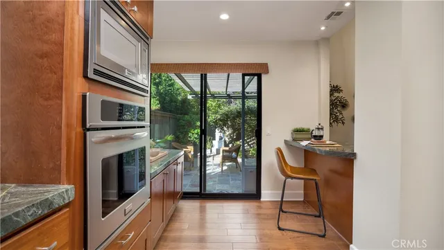 a kitchen with stainless steel appliances granite countertop wooden cabinets a sink and dishwasher a stove with wooden floor