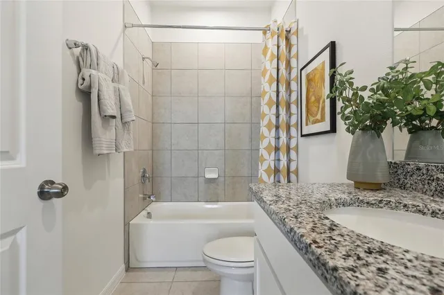 a bathroom with a granite countertop bathtub shower and toilet