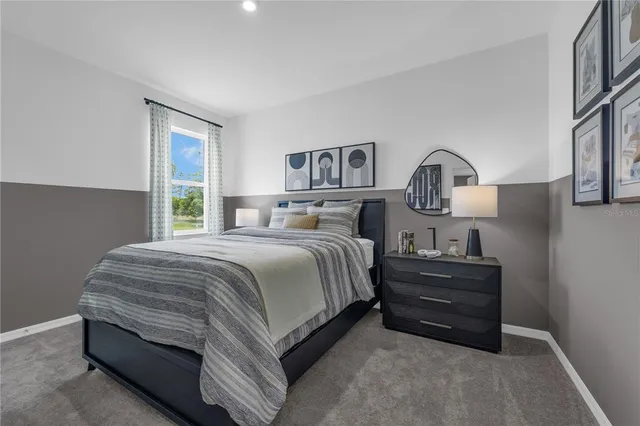 a spacious bedroom with a bed table and a window