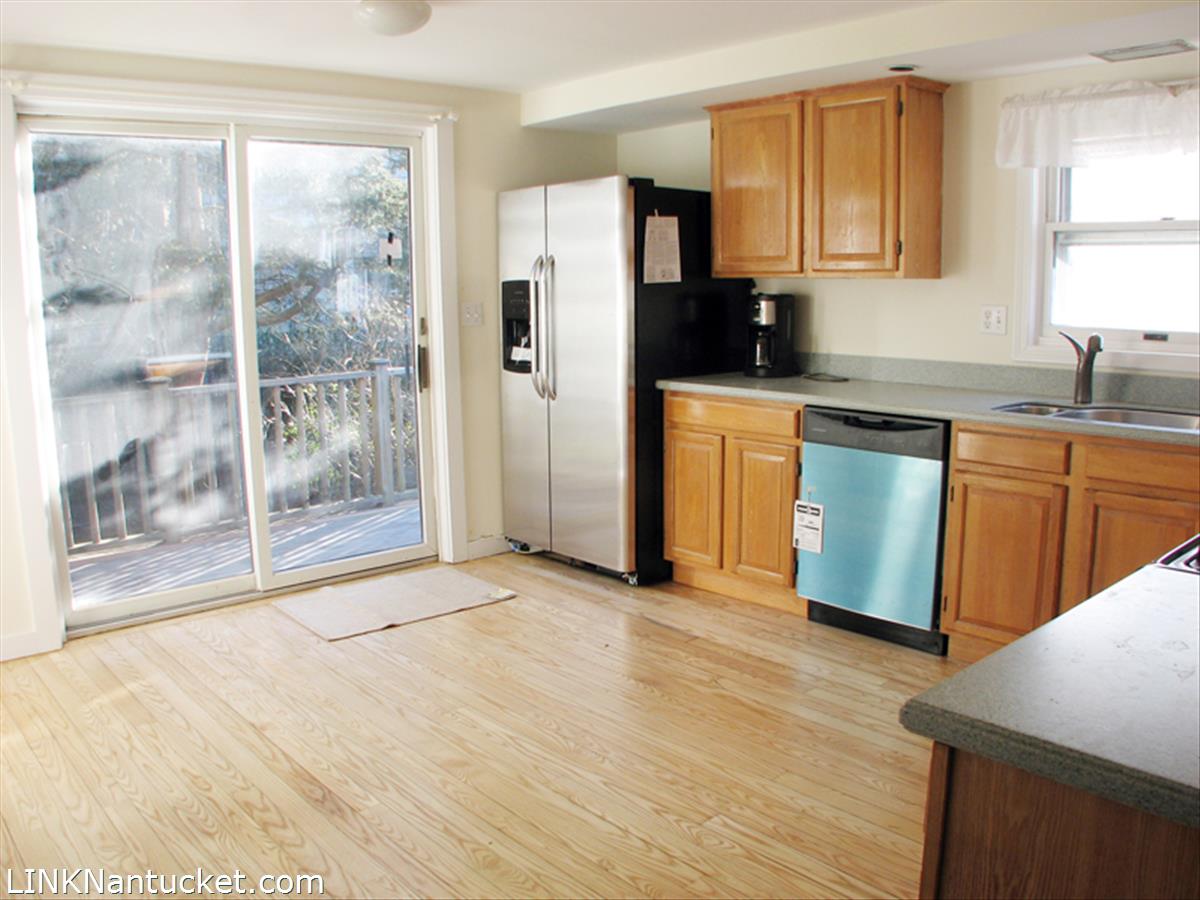 31 Surfside Road Nantucket, MA 02554 - Photo 2 of 9 Open kitchen with wood floors and sliding door to a deck.