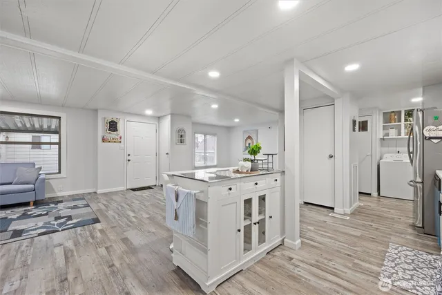 a kitchen with stainless steel appliances a stove top oven a refrigerator a sink and dishwasher with wooden floor