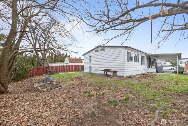 a backyard of a house with large trees and barbeque oven