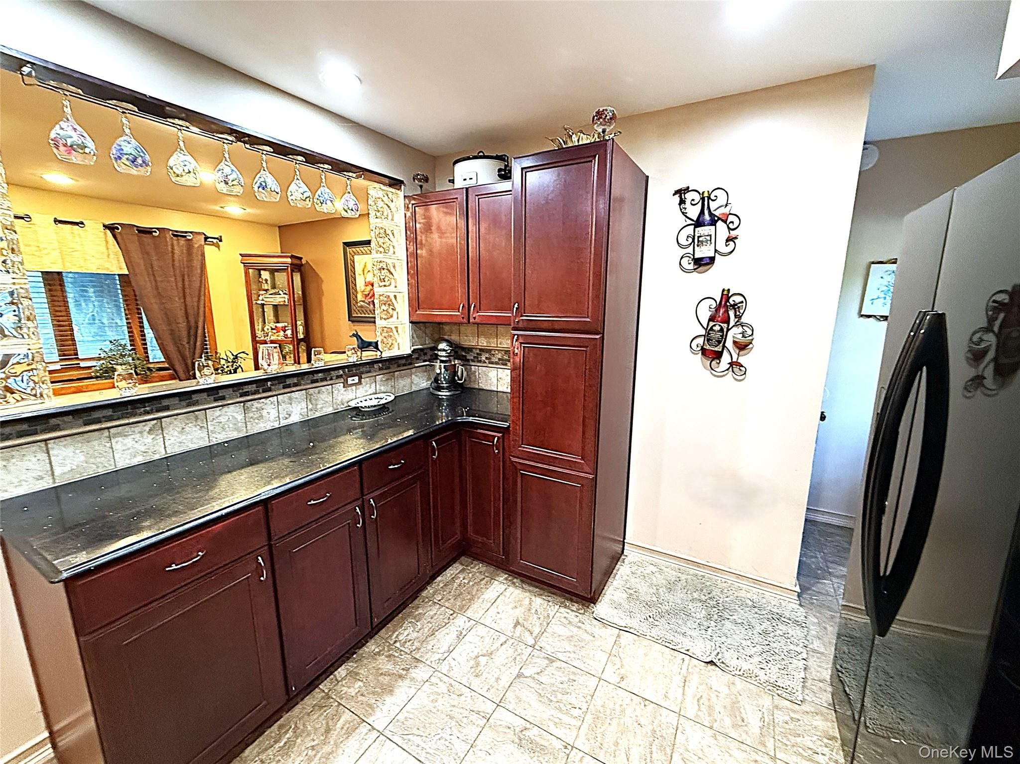 1 Heston Road Shirley, NY 11967 - Photo 12 of 32 Kitchen featuring dark wood-finish cabinetry, dark countertops, a tiled backsplash, and light-toned floor tiles