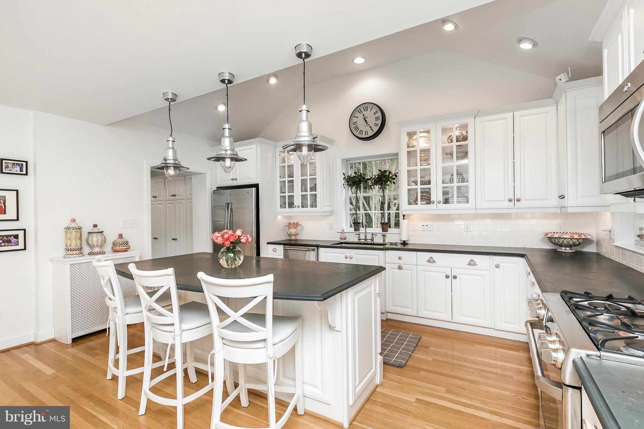 5700 Kenmore Road Baltimore, MD 21210 - Photo 11 of 30 a kitchen with stainless steel appliances kitchen island granite countertop a stove a sink a dining table and chairs with wooden floor