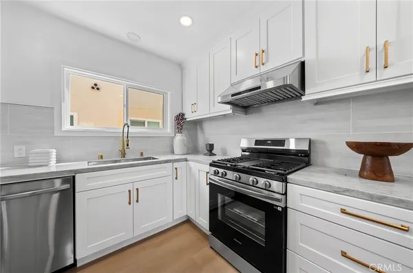 a kitchen with stainless steel appliances granite countertop a sink a stove and cabinets