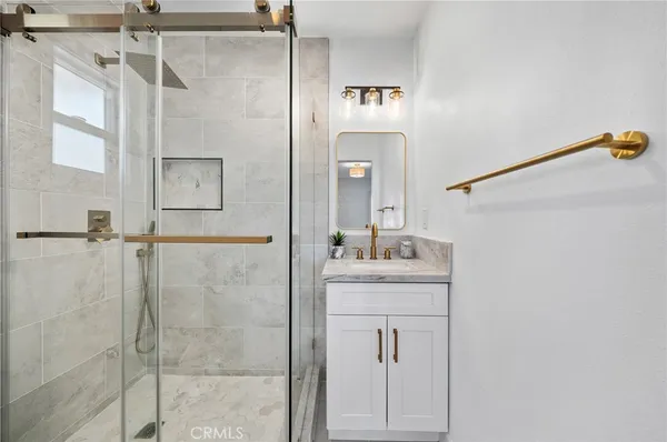 a bathroom with a granite countertop sink a mirror and shower