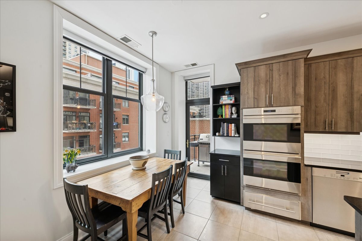30 West Erie Street, Unit 601 Chicago, IL 60654 - Photo 13 of 30 a kitchen with a stove a refrigerator and a dining table with wooden floor