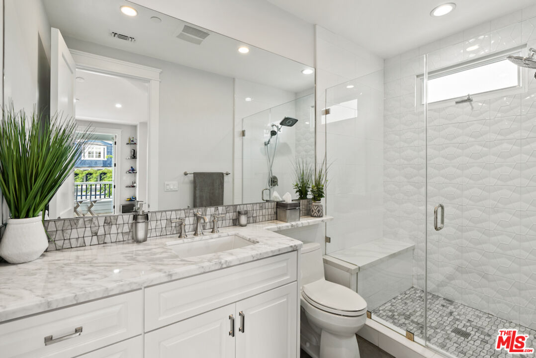 592 30th Street Manhattan Beach, CA 90266 - Photo 35 of 57 a bathroom with a granite countertop sink a toilet a large mirror and shower
