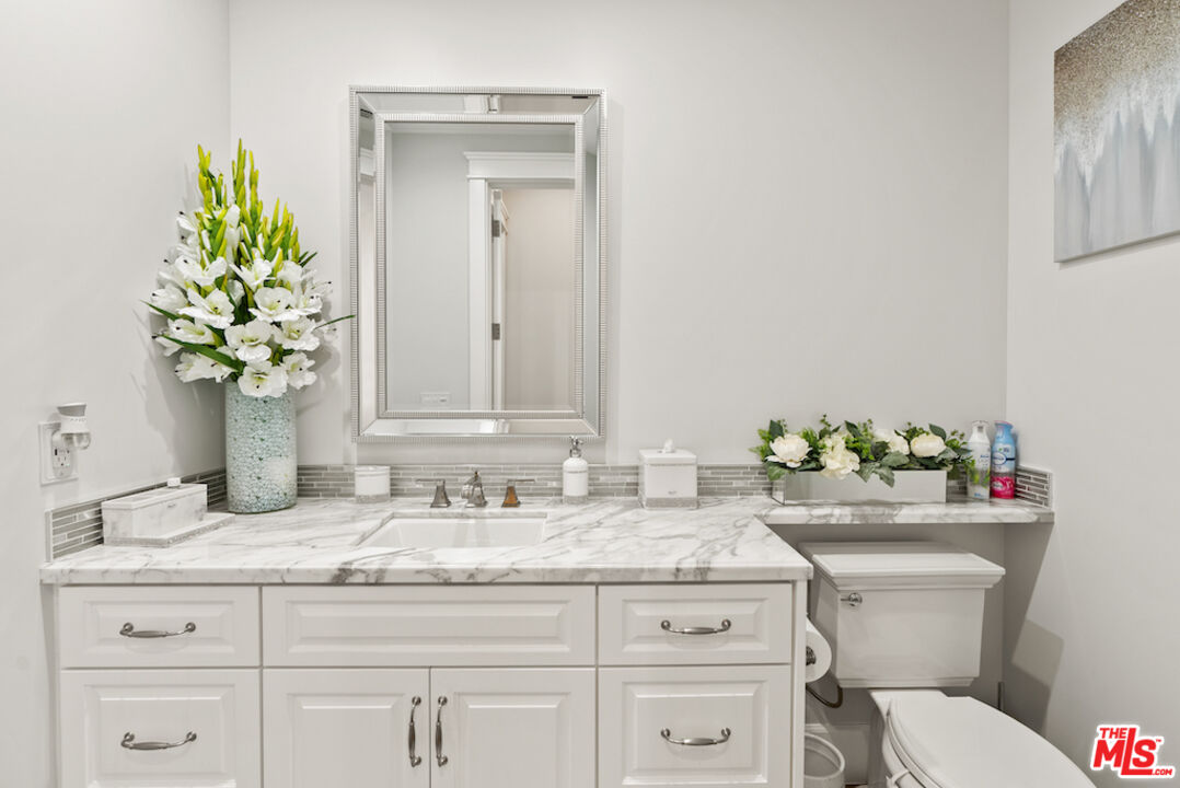 592 30th Street Manhattan Beach, CA 90266 - Photo 41 of 57 a bathroom with a granite countertop toilet sink and mirror