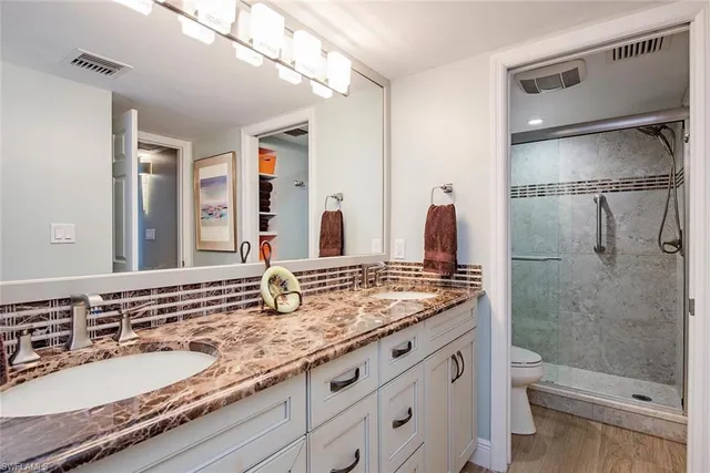 a bathroom with a granite countertop sink a toilet a mirror and shower