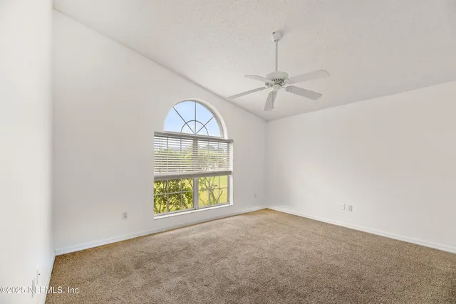 an empty room with windows and fan