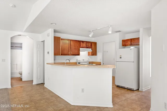 a view of kitchen with stainless steel appliances granite countertop refrigerator sink and cabinets