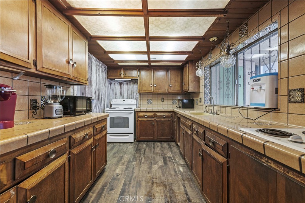 15374 Gaskell Road Rosamond, CA 93560 - Photo 49 of 74 a large kitchen with stainless steel appliances granite countertop a stove a sink dishwasher and cabinets with wooden floor