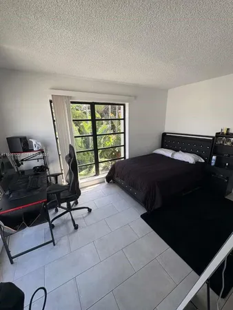 a bedroom with a bed a table and a large window