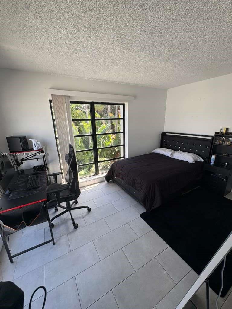 1220 71st Street, Unit 38 Miami Beach, FL 33141 - Photo 15 of 22 a bedroom with a bed a table and a large window