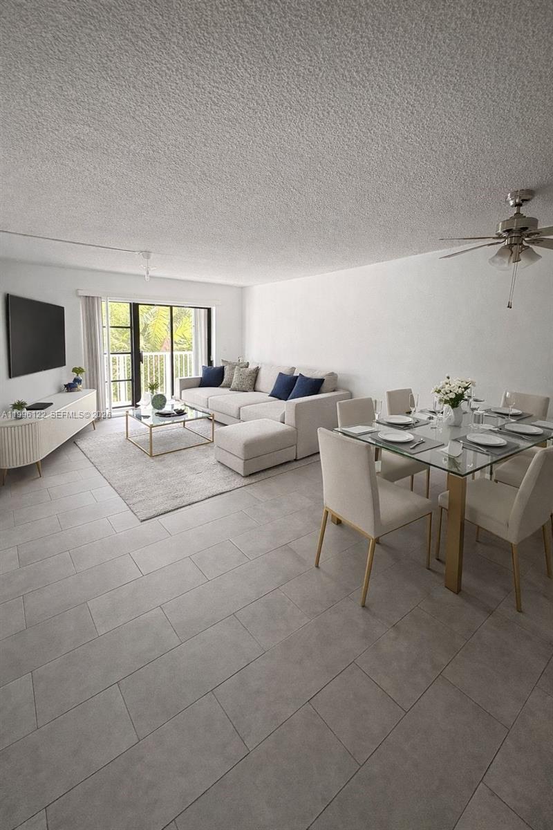 1220 71st Street, Unit 38 Miami Beach, FL 33141 - Photo 5 of 22 a living room with couches a coffee table a flat screen tv and a large window with kitchen view